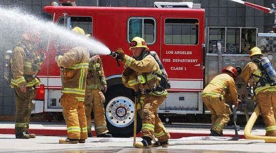 Firemen deploying hose at scene of fire