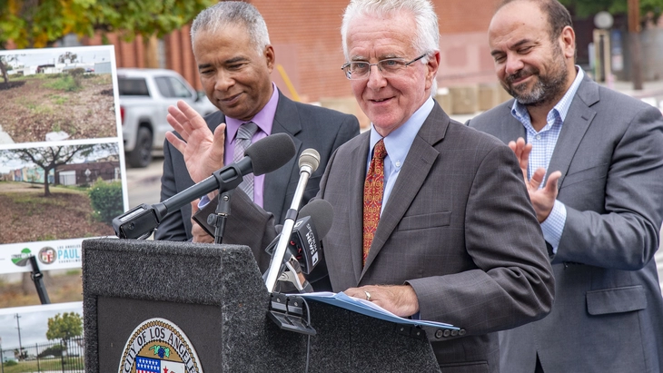 Council President Krekorian speaks at lectern as Streets LA Chief Keith Mozee and former State Assemblymember Adrin Nazarian listen and applaud.