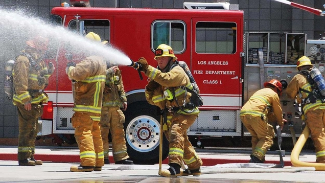 Firemen deploying hose at scene of fire
